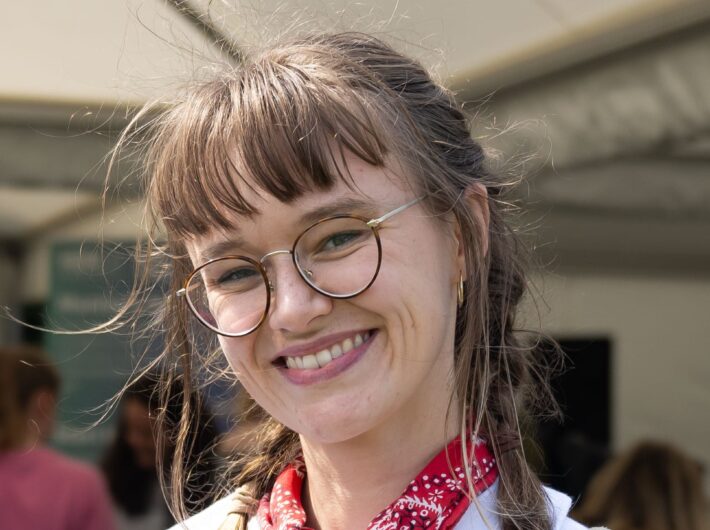 A smiling woman with light brown hair and glasses.