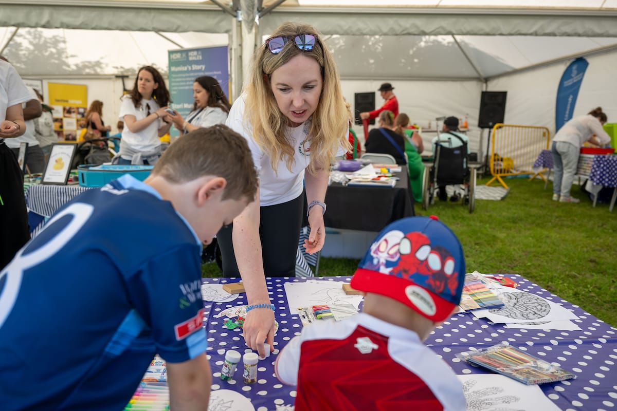 One women and two children looking down at an activity on the table.