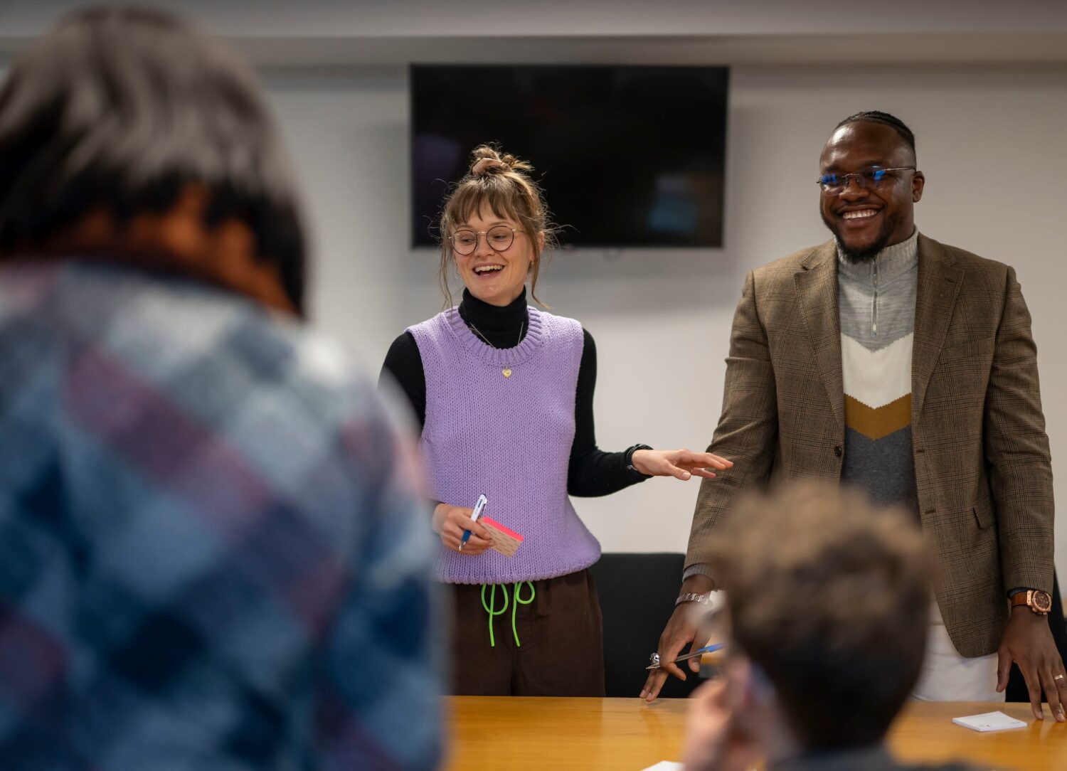 Two people standing at a table talking and smiling.