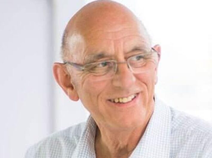 A bald man smiling to somewhere off camera