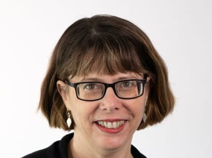 A woman with brown hair and glasses smiling at the camera
