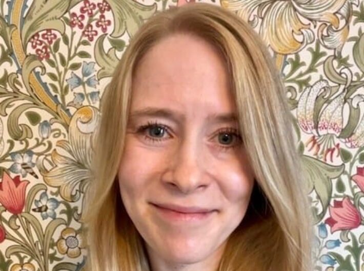 A women with long blonde hair smiling at the camera