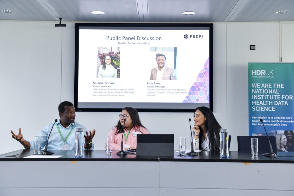 Two women and one man speaking at a panel session in front of a projected image.