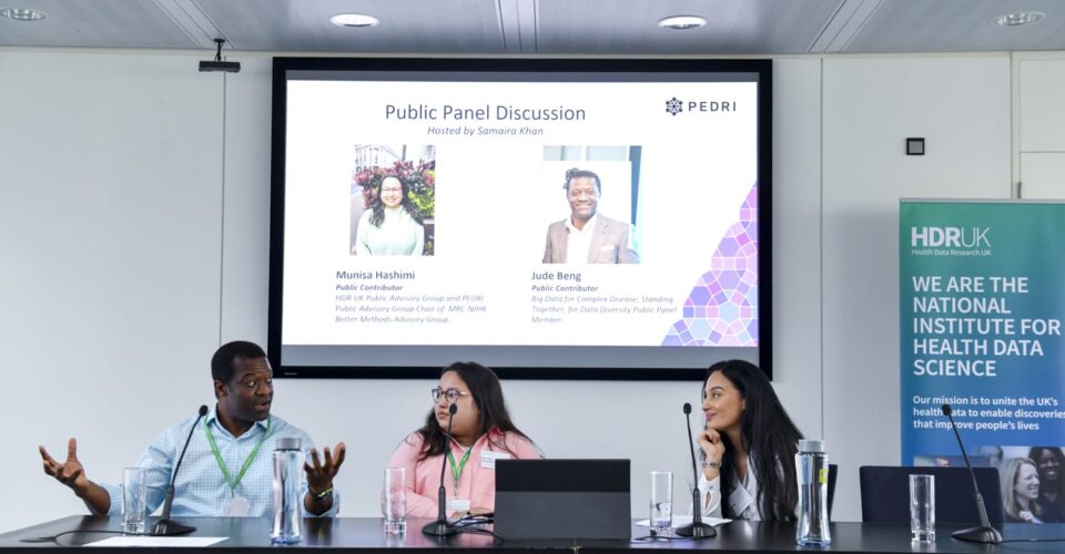 Two women and one man speaking at a panel session in front of a projected image.