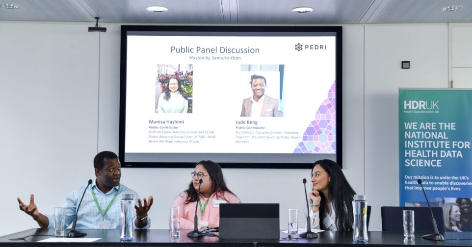 Two women and one man speaking at a panel session in front of a projected image.