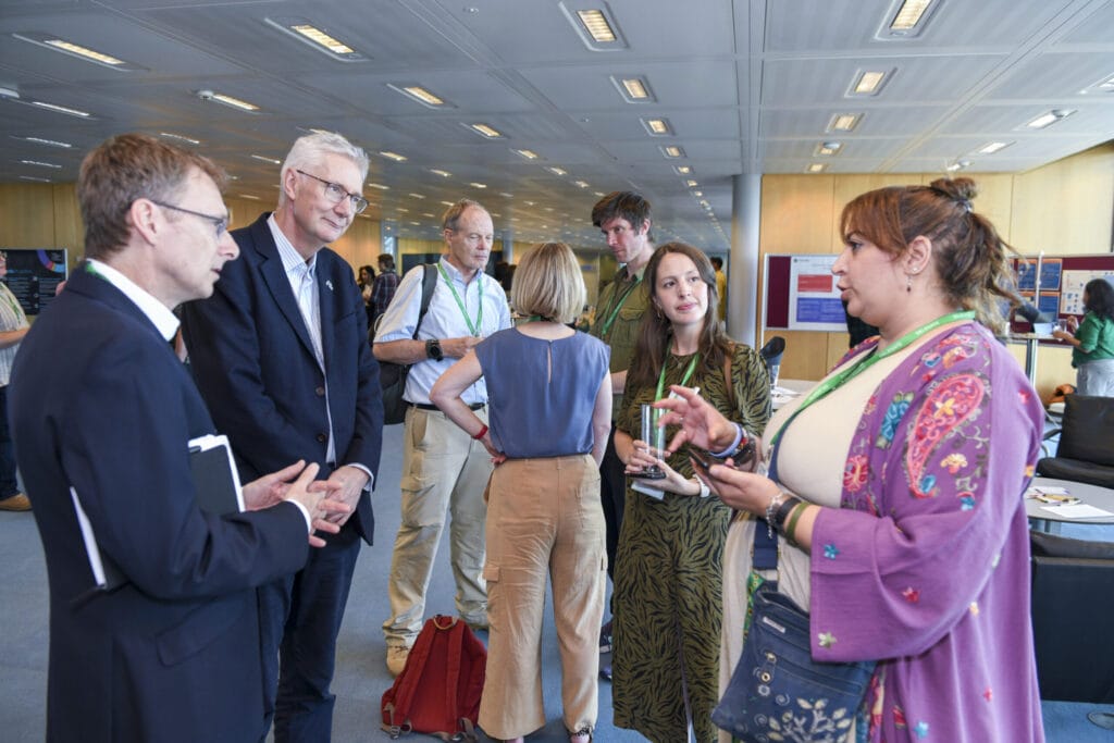 Group of four people standing in circle talking.