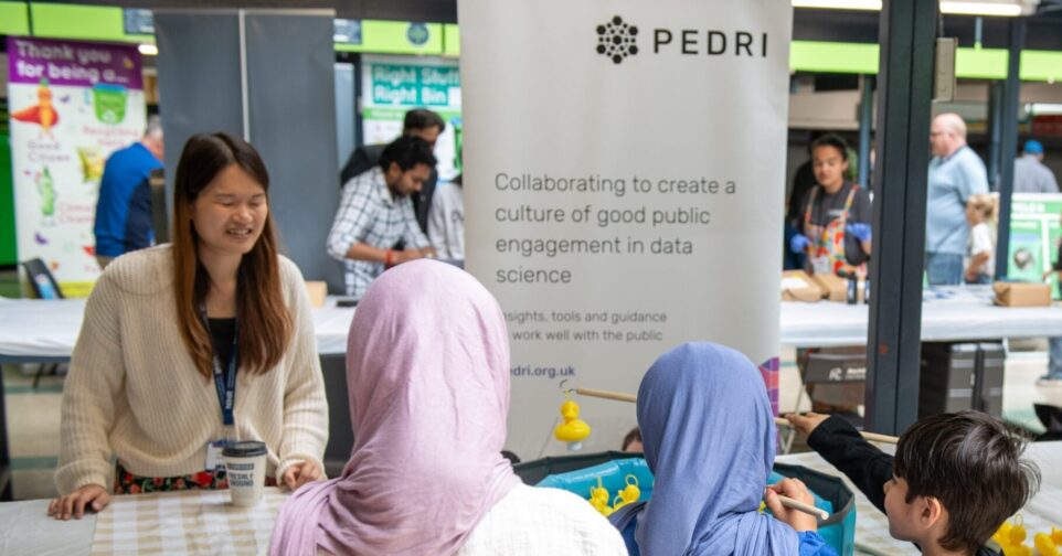 A group of young people play speak across a table with an adult.