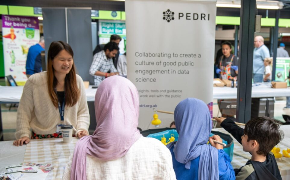 A group of young people play speak across a table with an adult.