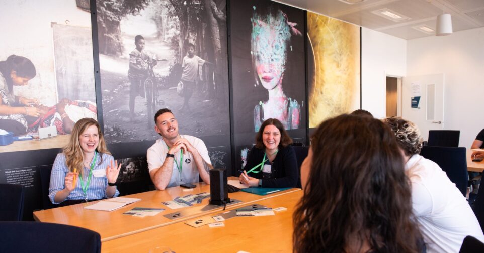 A group of people sit around a table smiling