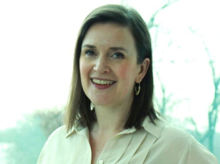A woman with brown hair smiles at the camera