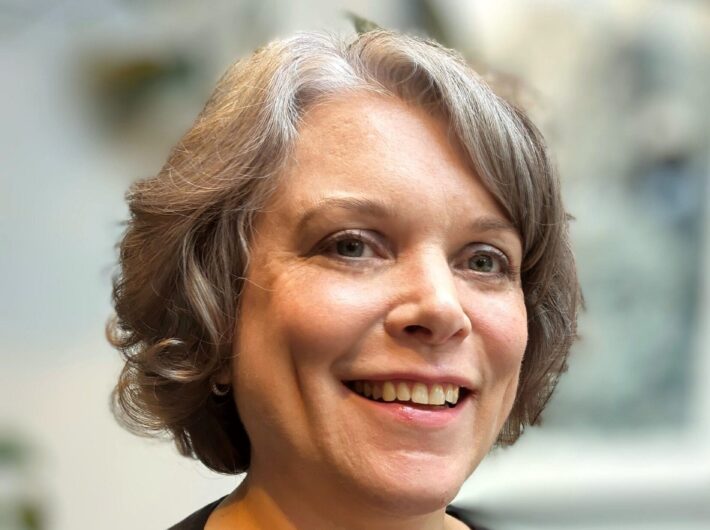 A woman with light brown hair smiles at the camera