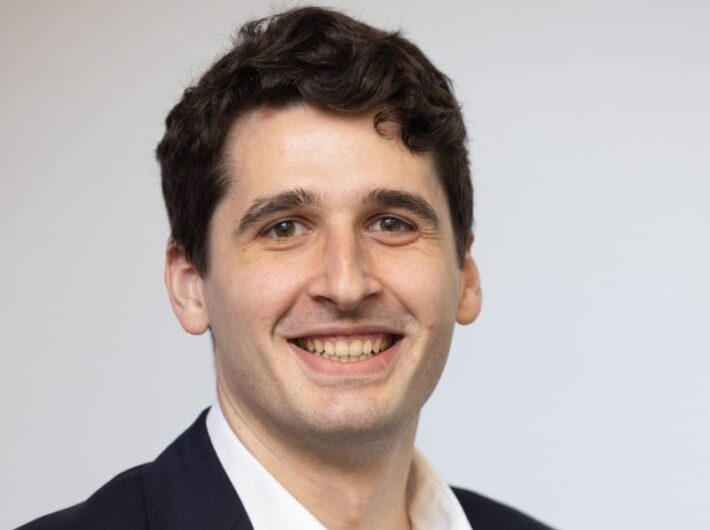 Man with dark hair smiling at the camera